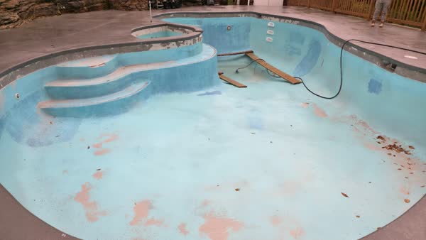 Pool with worn plaster and equipment ready for renovation
